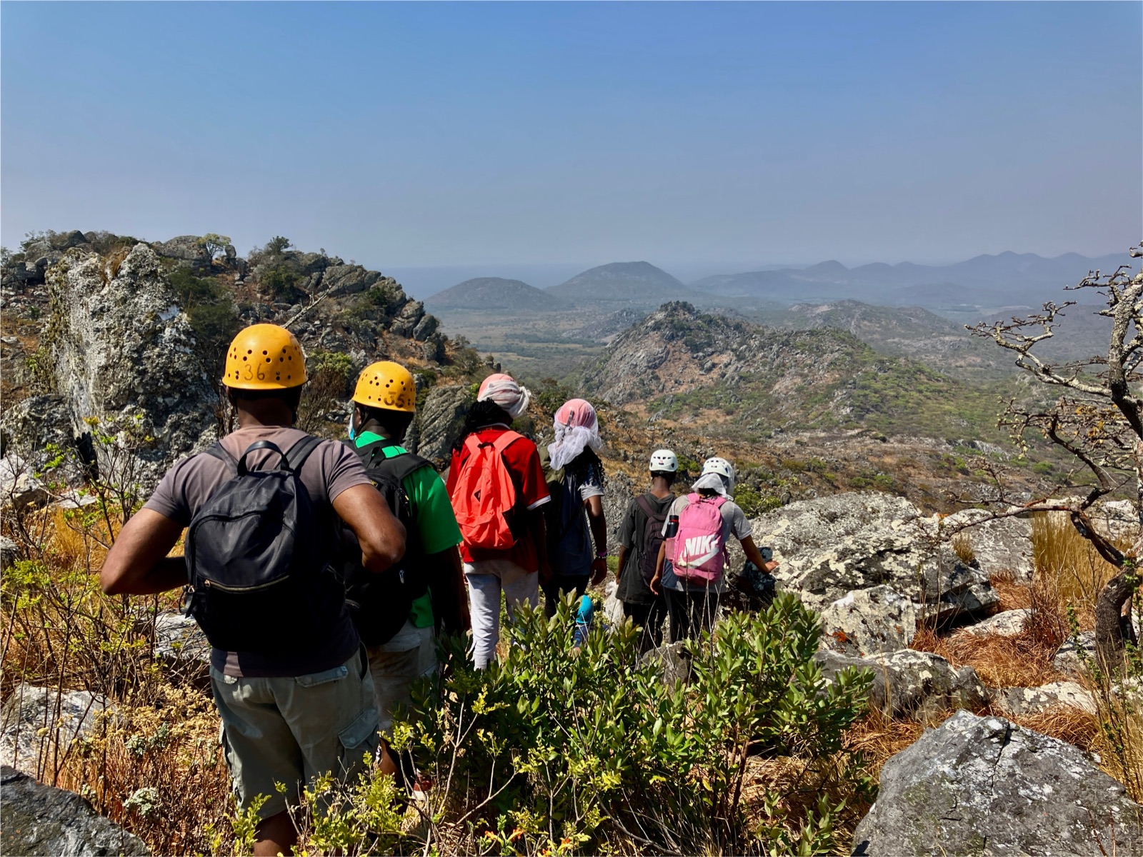 Young people wearing helmets hiking through rocky terrain